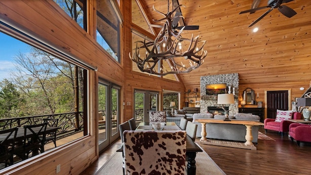 Un intérieur spacieux en bois, comprenant un coin repas, une cuisine agrémentée d’éléments en pierre et un grand lustre.