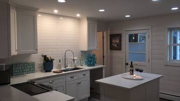 A modern kitchen with white cabinetry, a central island, and recessed ceiling lights.