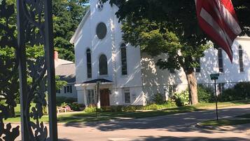 A white church with a steeple and a flagpole with an American flag.