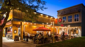 An outdoor dining area with tables and chairs, a sign indicating the restaurant is open, and a building with a sign that reads "OPEN". - The Frankfort Surf Cottage (Frankfort)