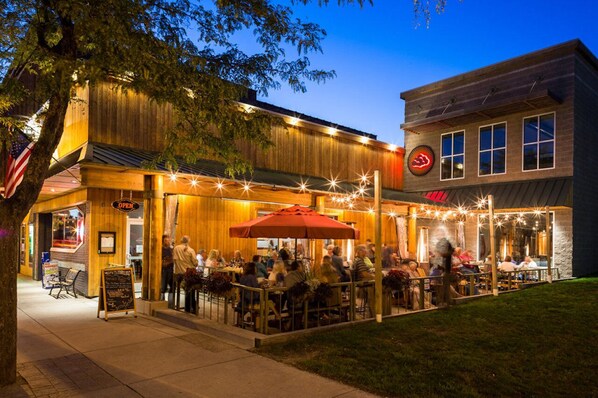 An outdoor dining area with tables and chairs, a sign indicating the restaurant is open, and a building with a sign that reads "OPEN". - The Frankfort Surf Cottage (Frankfort)