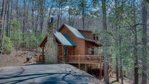 Une cabane avec des fondations en pierre, un revêtement extérieur en bois et un balcon.