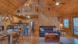 L’intérieur d’une cabane en bois comprend un coin repas, une cuisine, un salon et un escalier.