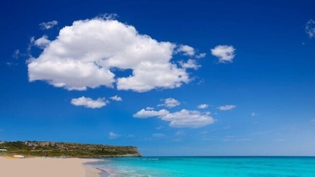 A beach with clear turquoise waters and a sandy shore.