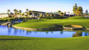 A golf course with a pond, green hills, and buildings in the background. - 2BD/Flagstaff - Full Kitchen, Living Room, W/D and Balcony! (Flagstaff)