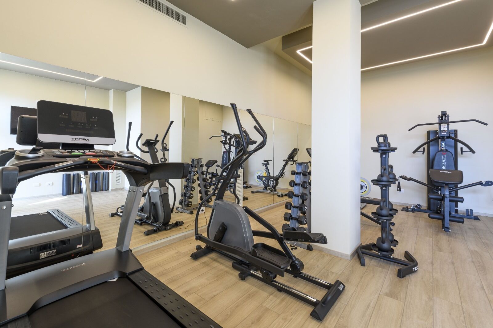 Ein modernes Fitnessstudio mit verschiedenen Cardio- und Krafttrainingsgeräten, darunter Laufbänder, Crosstrainer und Kraftgeräte.