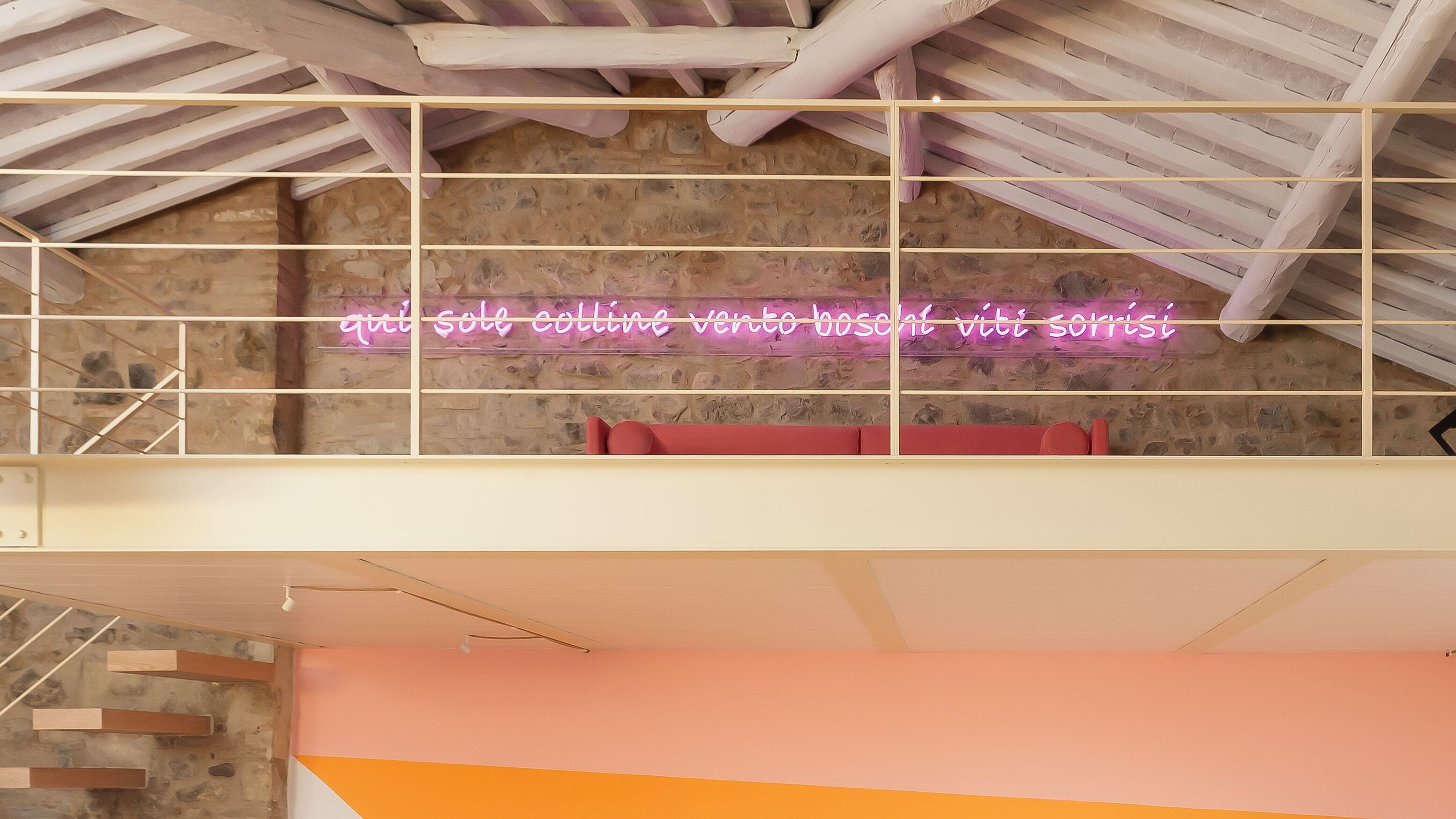 Ein Zimmer mit einer Steinwand, einem Neonlicht und einer roten Bank.