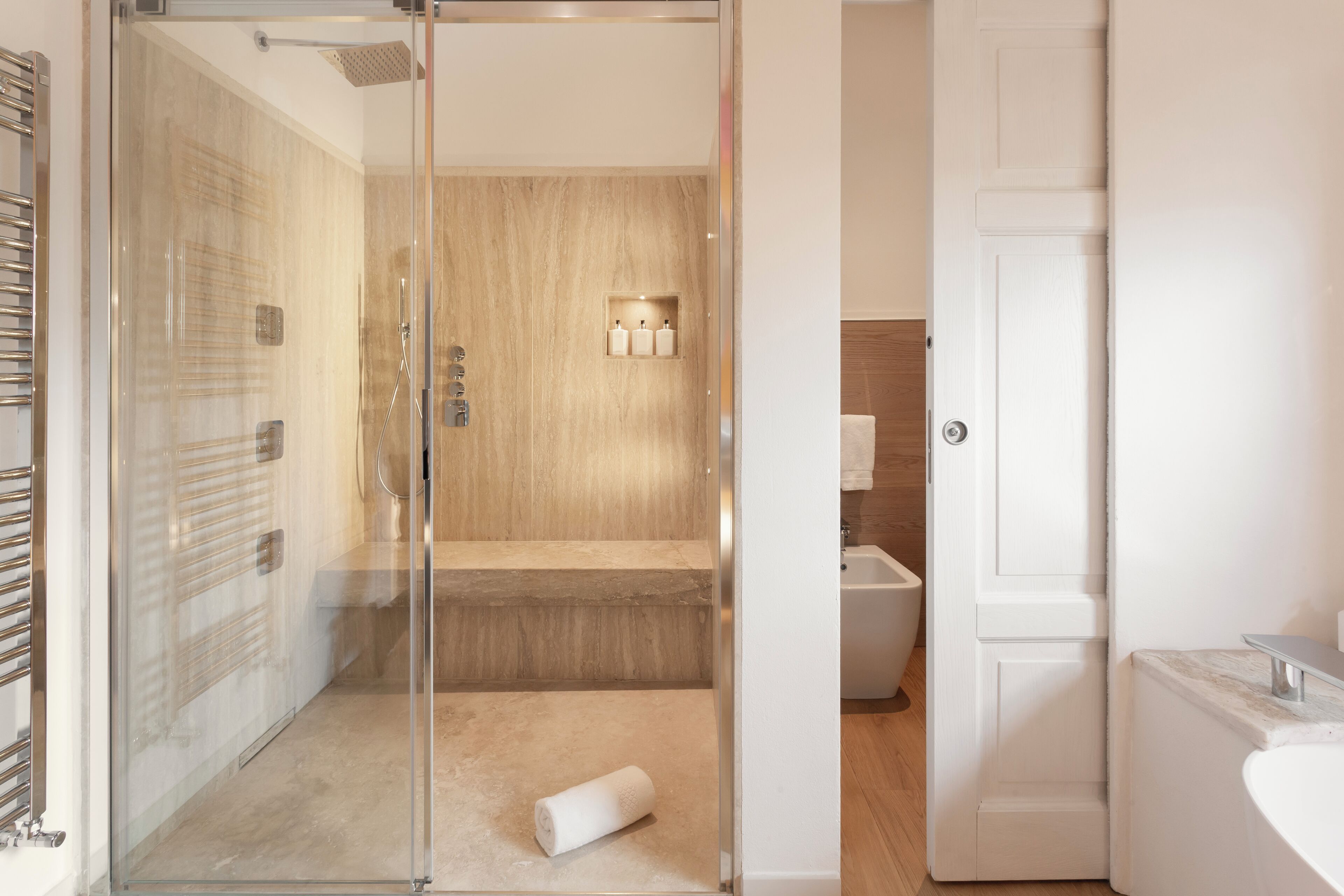 A modern bathroom with a glass-enclosed shower, a toilet, and a sink.