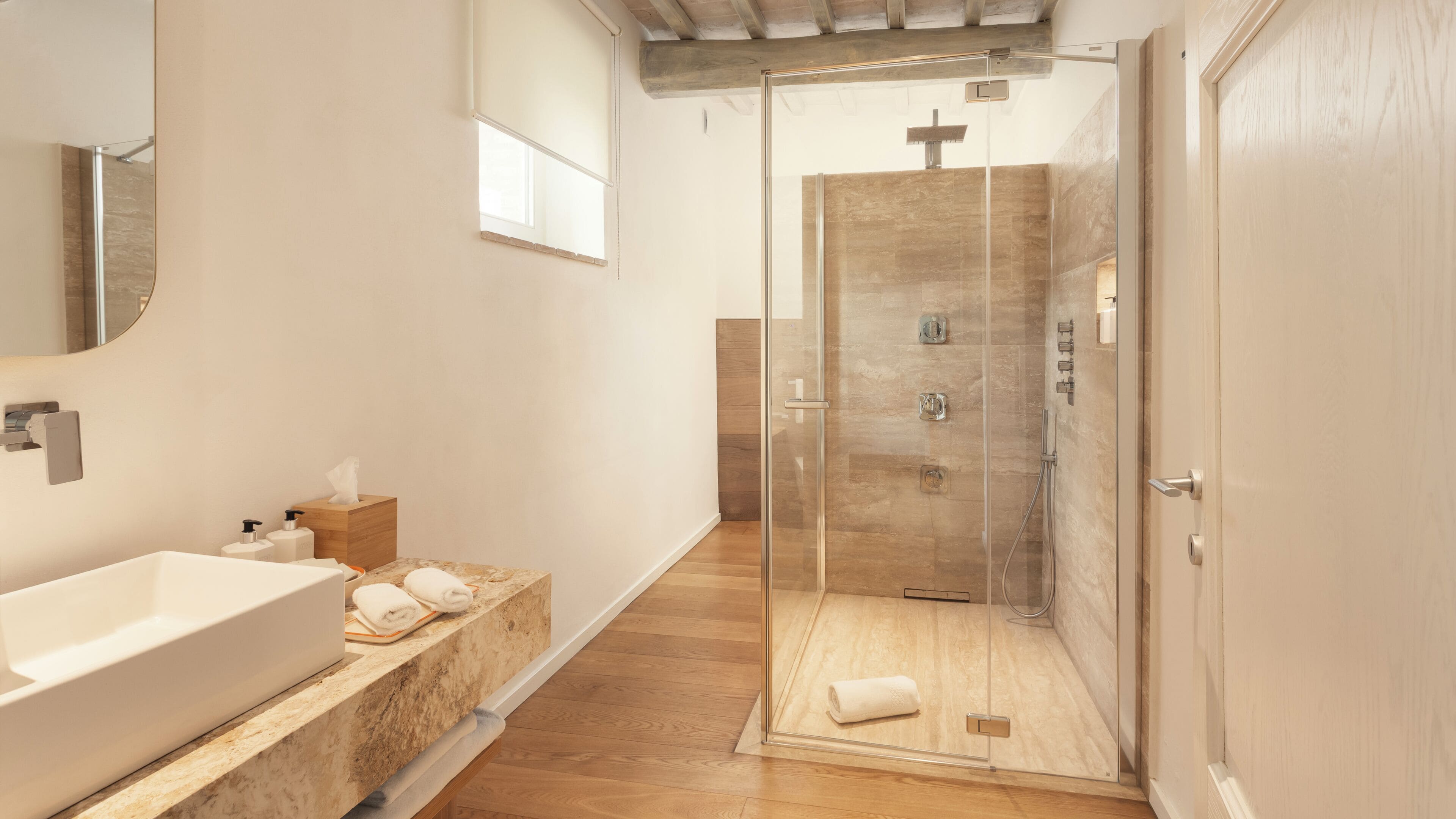 A modern bathroom with a glass-enclosed shower, a large sink, and a wooden vanity.