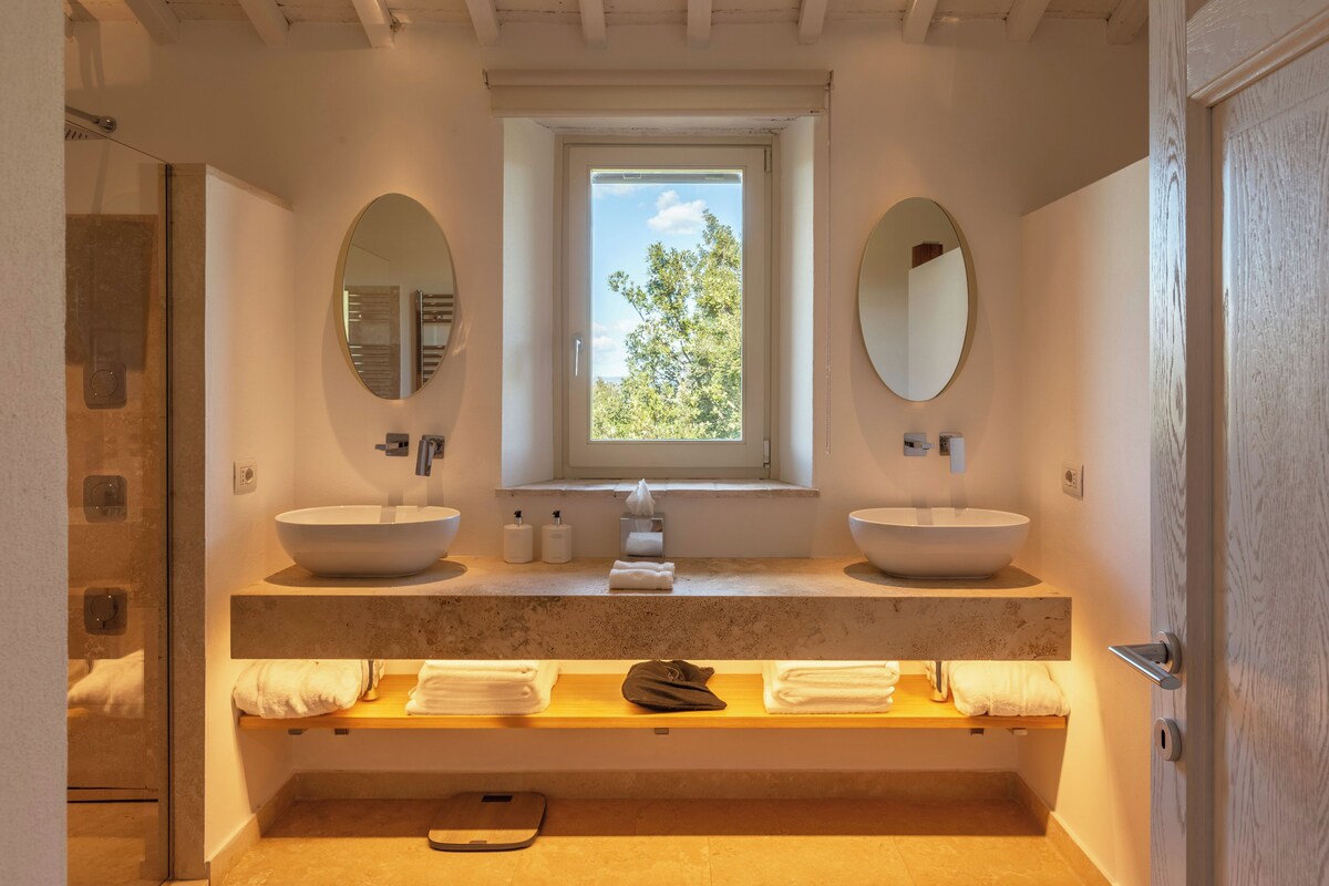 A modern bathroom with two sinks, a window, and a towel rack.
