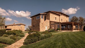 A stone house with a covered patio, a stone pathway, and well-maintained landscaping. - Mastrojanni Relais - Small Luxury Hotels of the World (Montalcino)