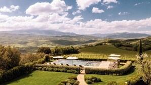 A pool surrounded by manicured gardens and vineyards, with a clear view of rolling hills in the background. - Mastrojanni Relais - Small Luxury Hotels of the World (Montalcino)