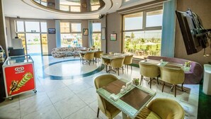 A hotel lobby with a circular seating area, a reception desk, and large windows offering a view of the outdoors. - Golden Moon Baku (Baku)