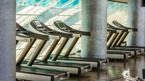 A row of treadmills in a gym with a glass ceiling and a "OUT OF ORDER" sign on one. - Golden Moon Baku (Baku)