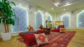 A room with a patterned carpet, a sofa set, a table with a lamp, and a potted plant. - Golden Moon Baku (Baku)