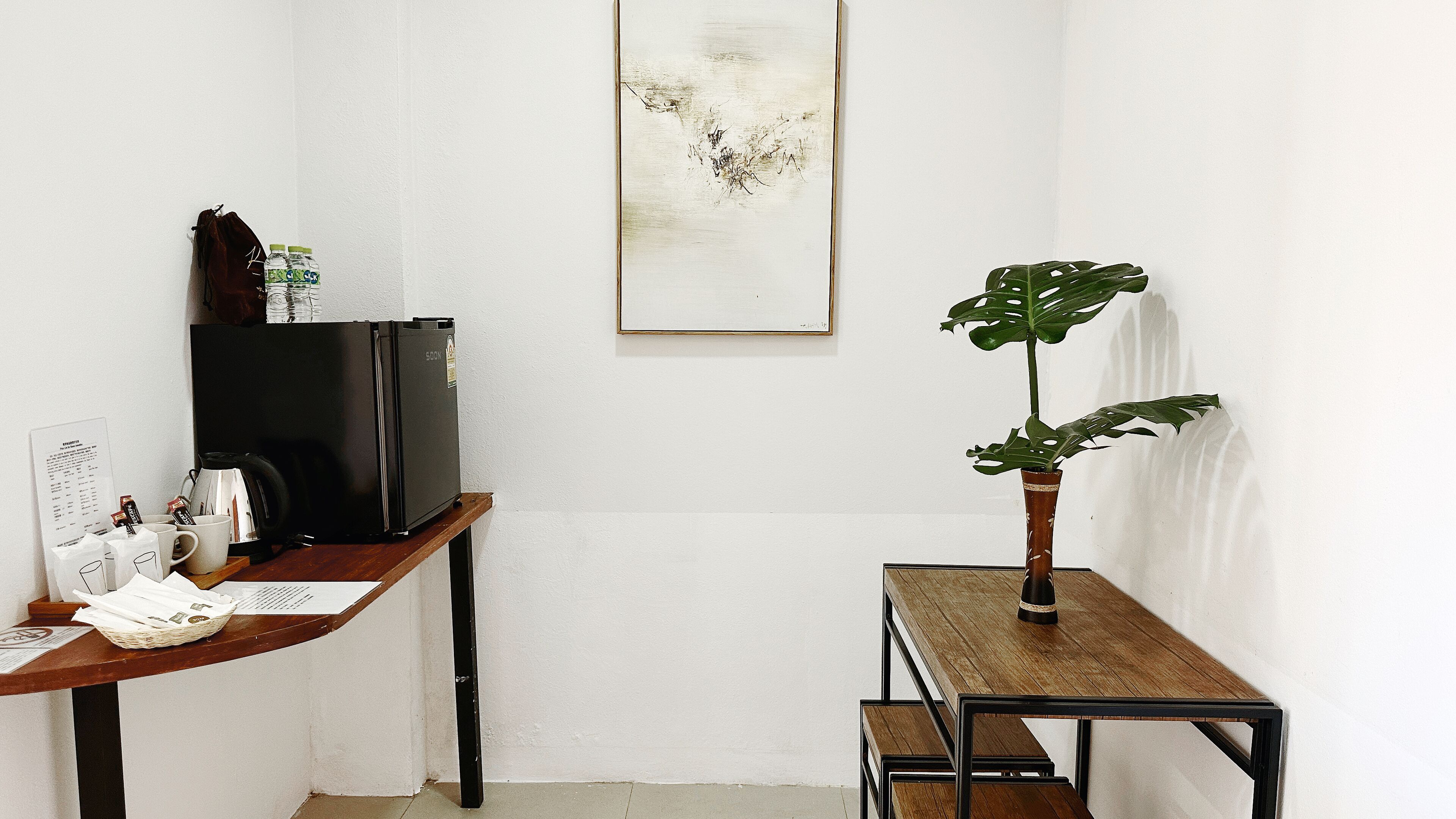 Een nette, kleine kamer met een bureau, een koffieapparaat en een plant.