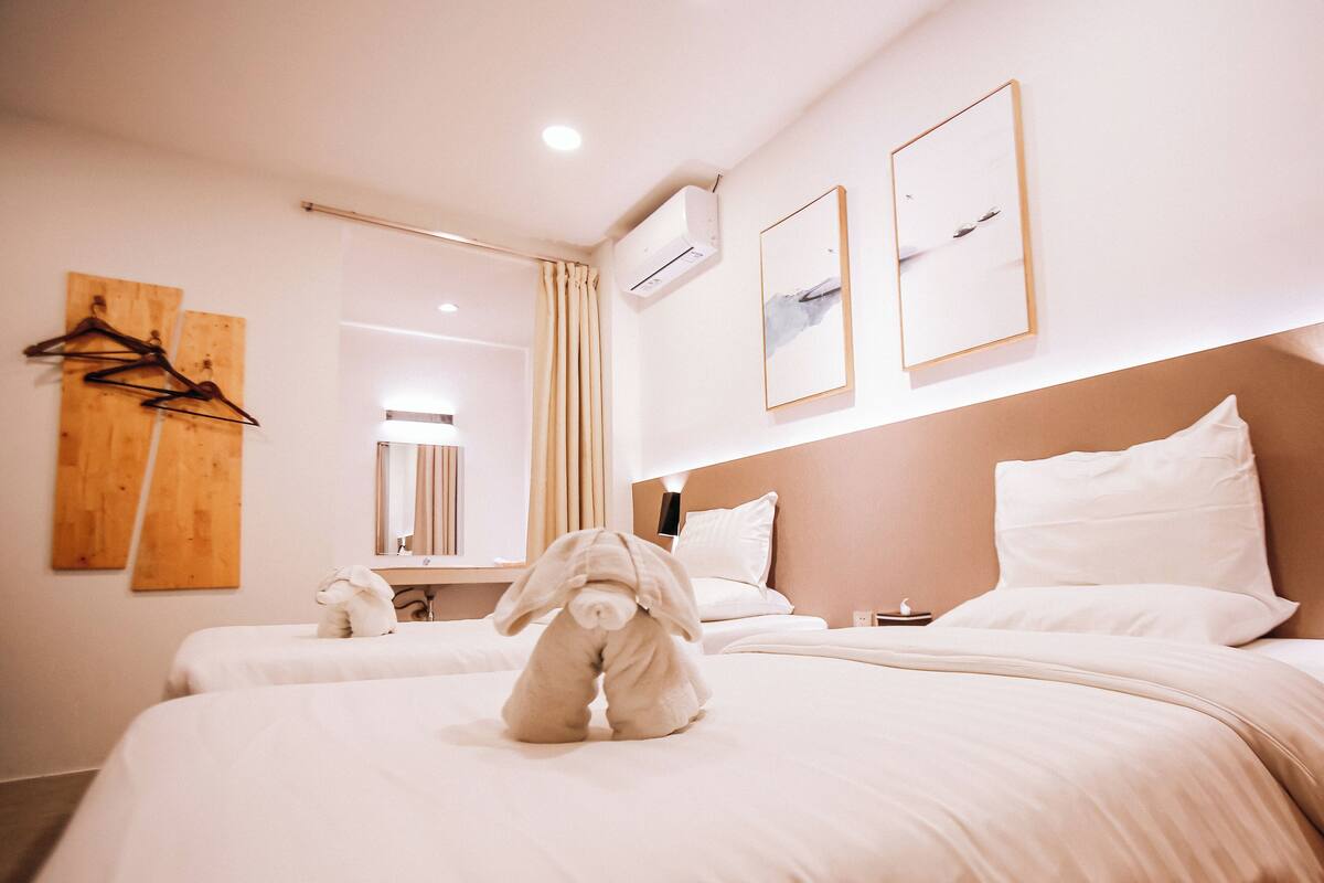 Quarto de hotel com duas camas, um espelho e obras de arte nas paredes.