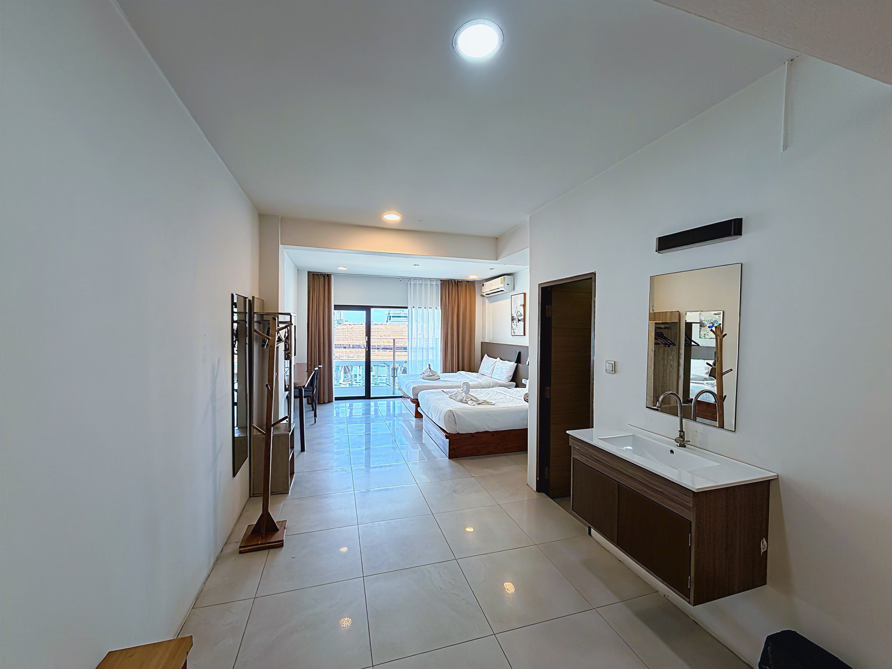A hotel room with a large bed, a bathroom with a mirror and sink, and a view through the door.
