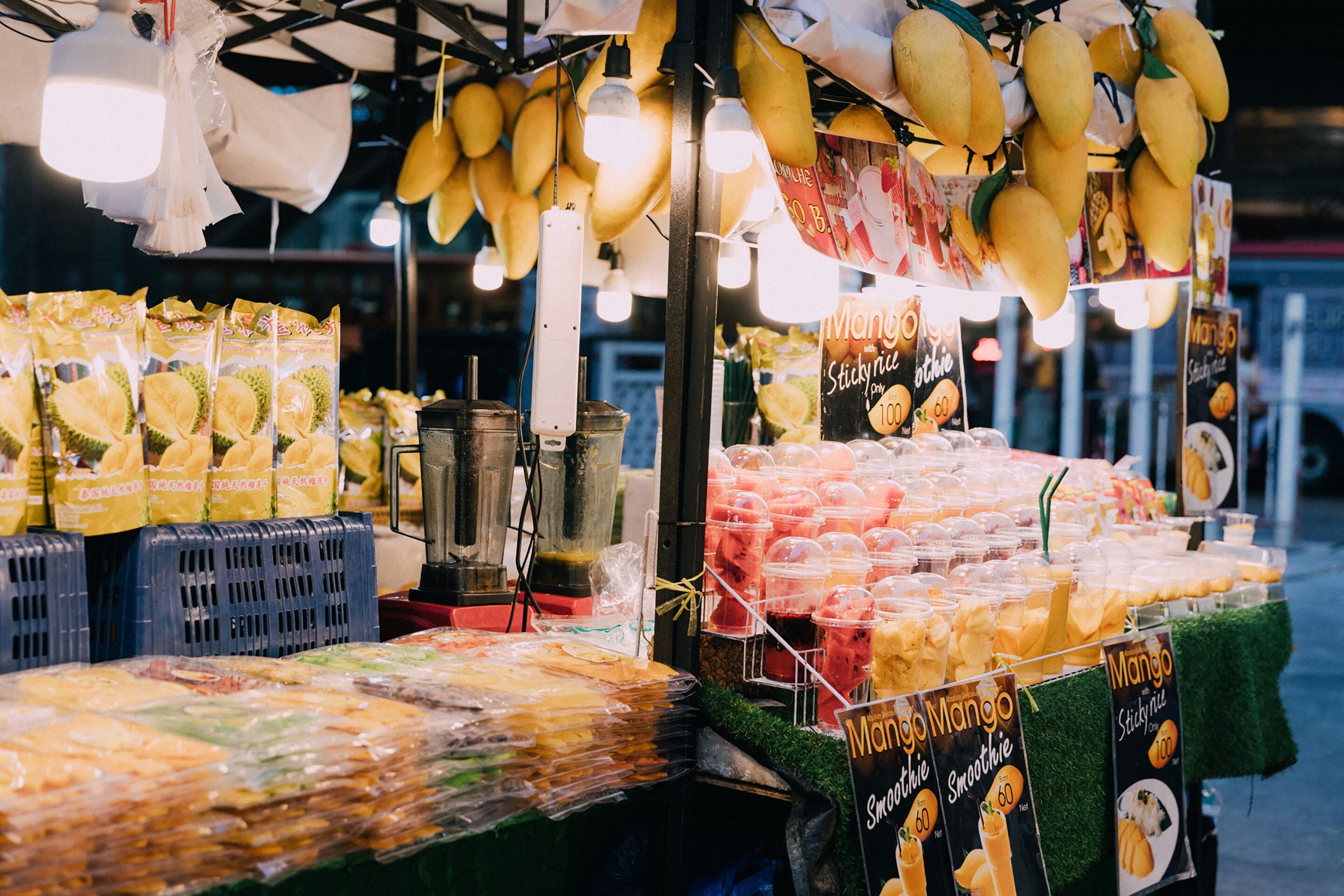 Un étal de fruits proposant une variété de fruits et de produits emballés.