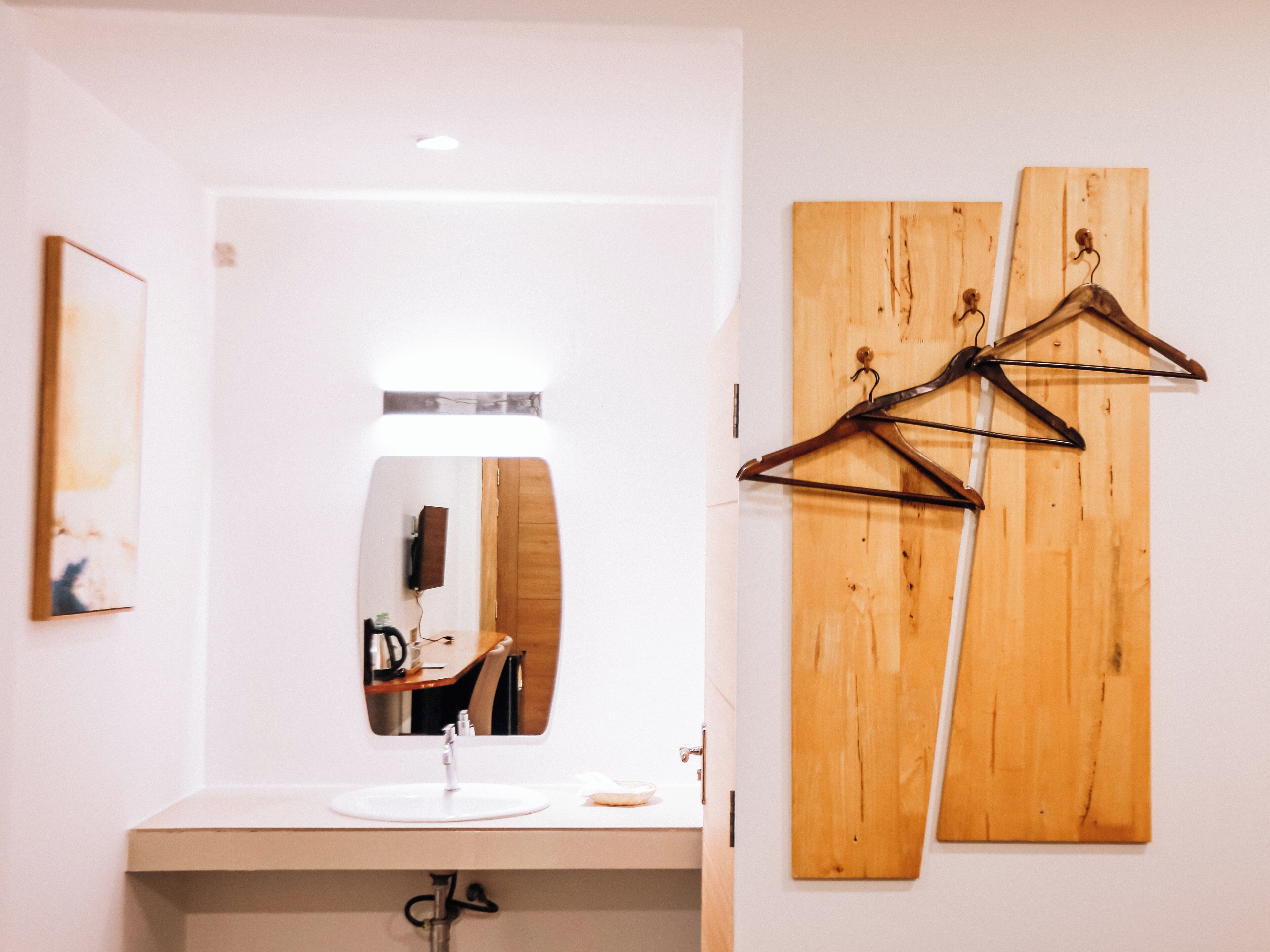 A bathroom with a sink, mirror, and wooden wall art.