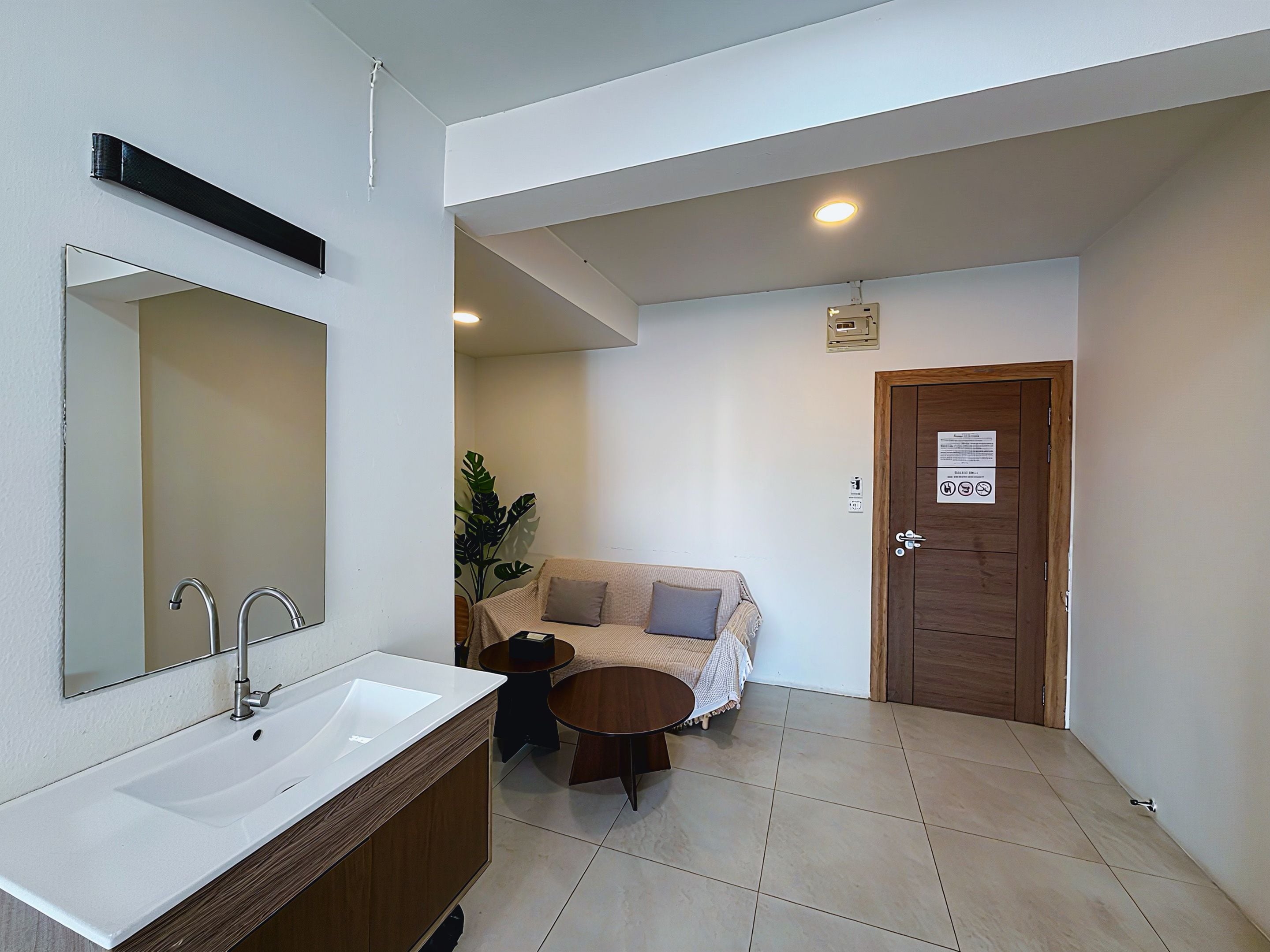 A bathroom with a white sink, a mirror, a wooden cabinet, a round table, and a couch.