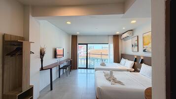 A hotel room with two beds, a desk, a TV, and a view of the city.