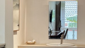 A bathroom with a large mirror, a sink, and a small basket on the countertop. - Key Hotel at Old City Center (Chiang Mai)