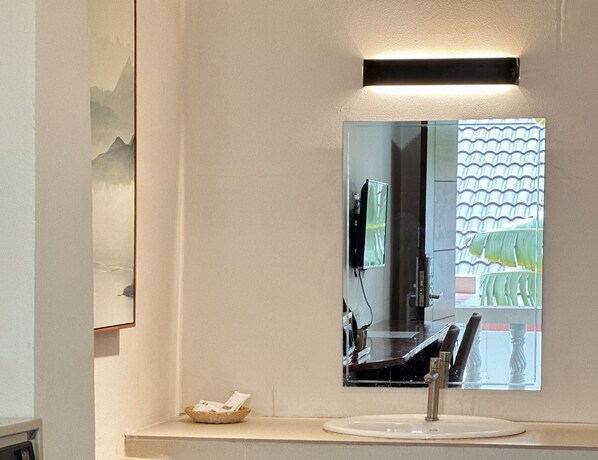 A bathroom with a large mirror, a sink, and a small basket on the countertop. - Key Hotel at Old City Center (Chiang Mai)