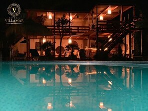 Una piscina al aire libre, sombrillas, sillones reclinables de piscina