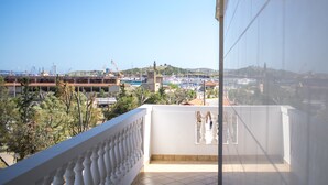 Ein Balkon mit weißer Brüstung, der auf einen Jachthafen mit Booten und Gebäuden blickt.