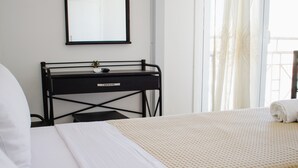 Ein Hotelzimmer mit zwei Betten, einem Schreibtisch, einem Spiegel und einem Fenster mit Vorhängen.