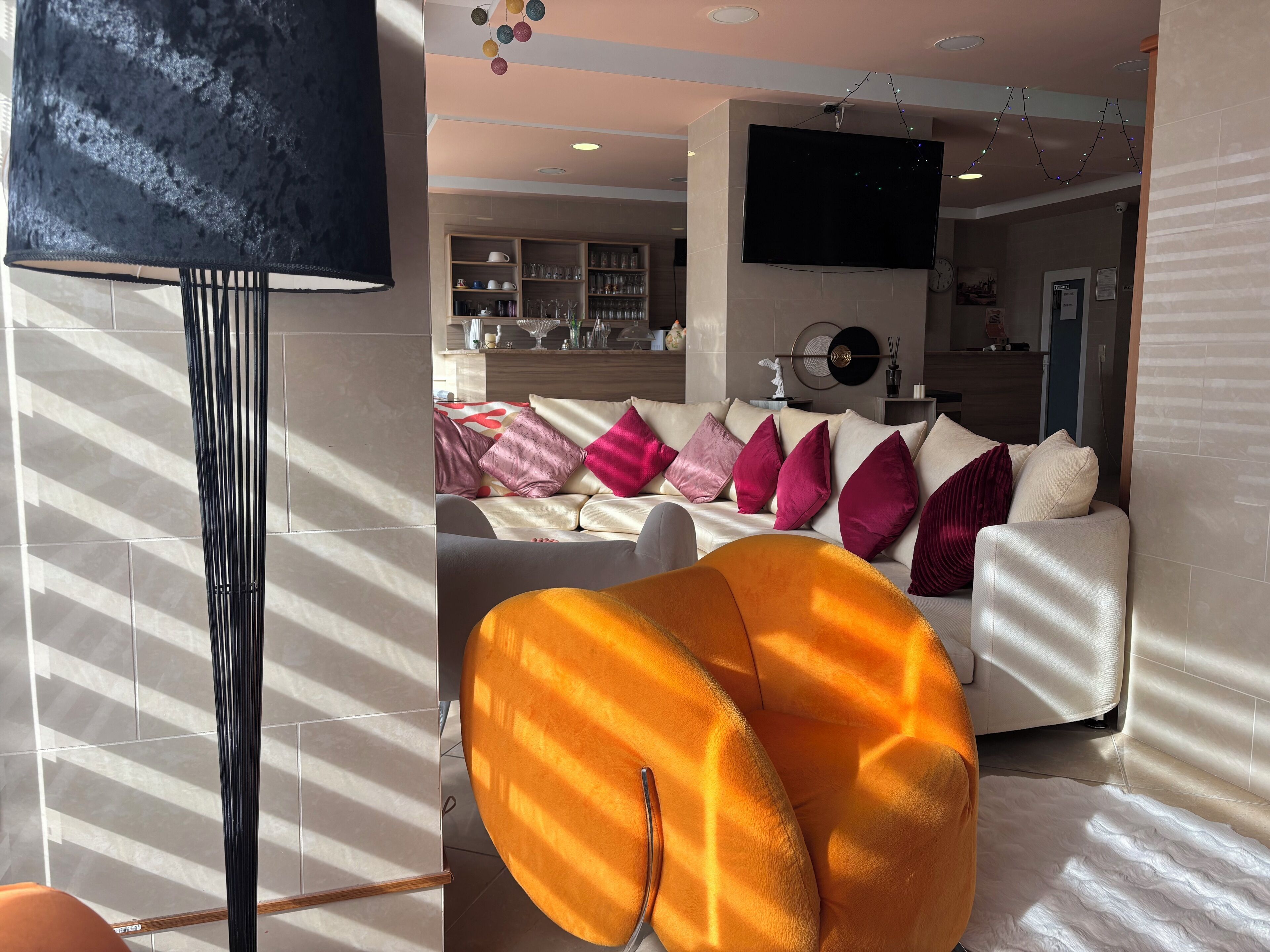 Un salon moderne avec un canapé, un grand téléviseur et une lampe décorative.