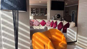 Un salon moderne avec un canapé, un grand téléviseur et une lampe décorative.