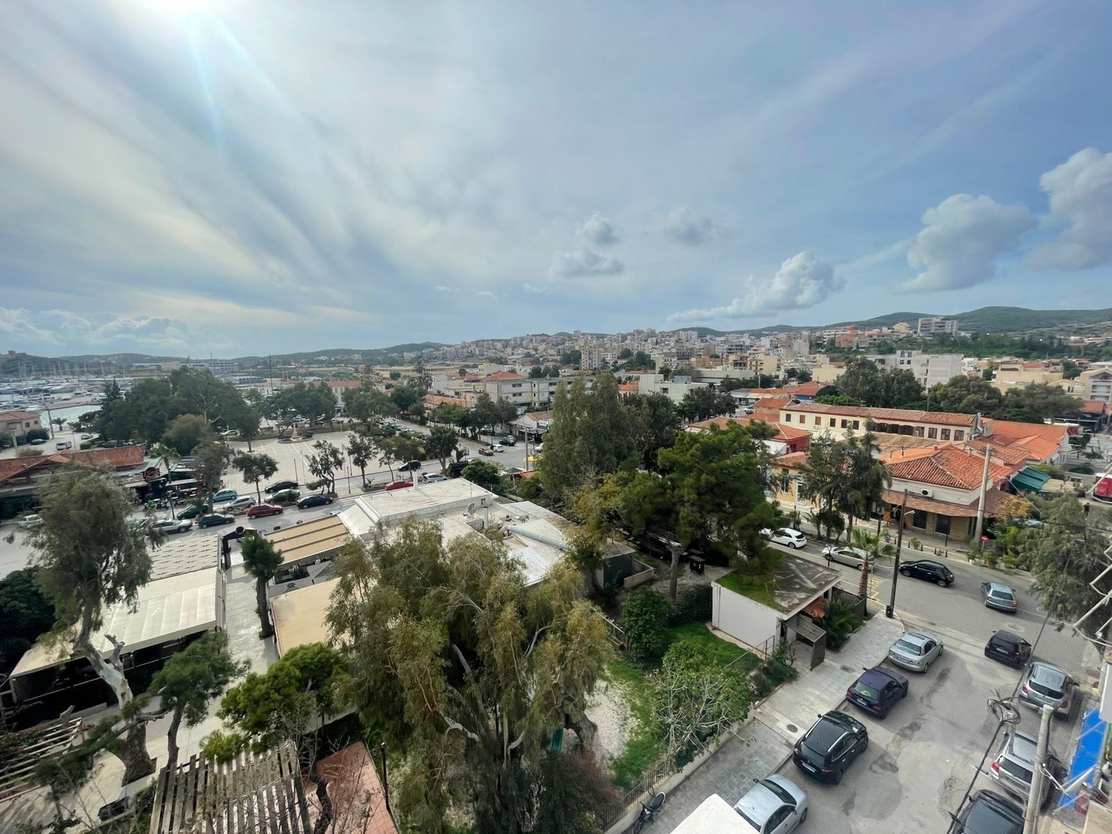 A cityscape with a mix of residential and commercial buildings, a parking lot, and a clear sky.