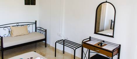A bedroom with a bed, a desk with a mirror, and a TV mounted on the wall.