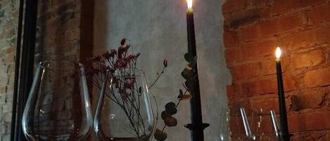 Una mesa dispuesta con copas de vino y velas, con un muro de ladrillo al fondo.