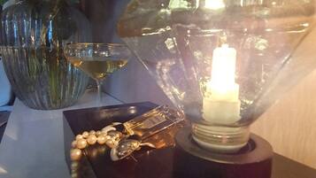 Una mesa con una lámpara decorativa, un florero con flores y una copa de vino blanco.