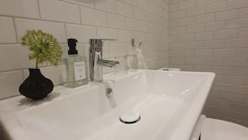 A modern bathroom with a white sink, a toilet, and a mirror.