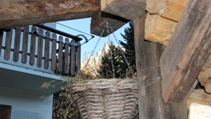 A balcony with a wooden railing and a woven basket hanging from it.