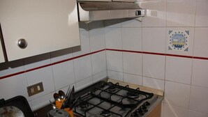 A kitchen with a gas stove, a range hood, and a tiled backsplash.