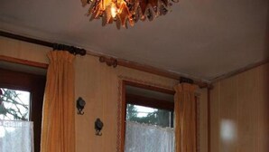 A bedroom with a large bed, wooden walls, and a window with curtains.