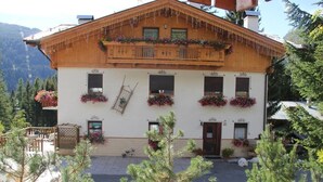 A traditional wooden chalet with a balcony, flower boxes, and a wooden fence.