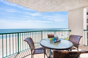 Enjoy the ocean view from this balcony with wicker chairs and a glass table.