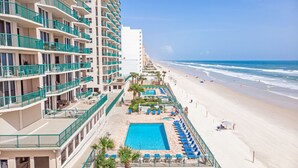 A hotel with multiple balconies, a pool area with sun loungers, and a beach view. - Oceanfront | Heated Pool-Twin Towers #1405 (Daytona Beach Shores)