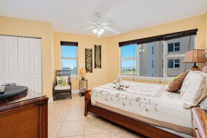 A bedroom with a bed, a ceiling fan, a window, and a view of a building. - Oceanfront | Heated Pool | Twin Towers 1405 (Daytona Beach Shores)