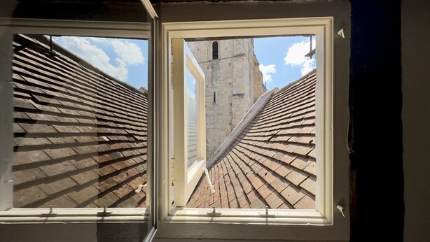 Un lucernario con vista su un edificio in pietra e un tetto in tegole.