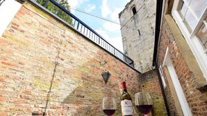 Un muro in mattoni con una bottiglia di vino e due bicchieri su un tavolo.