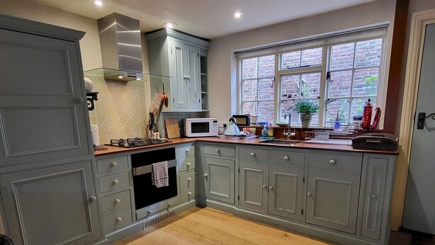 A kitchen with grey cabinets, a microwave, a stove, and a window with a view of the outside. - 7 Monk Bar Court YORK (York)