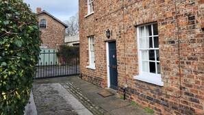 A traditional brick building with a dark blue door and white-framed windows. - 7 Monk Bar Court YORK (York)