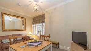 A cozy living room with a wooden table, books, a TV, a sofa, and a large mirror. - Apt 2, 71 Micklegate, YORK (York)